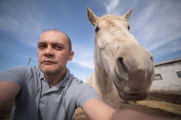 Fototapeta premium Portrait of a middle aged man with a horse on a ranch.