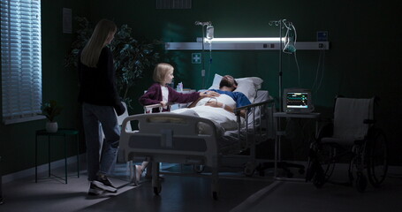 In hospital, mom and child sit near unconscious dad.