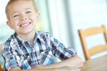 Portrait, smile and child in home, cute and happy for break, table and adorable boy in morning and...