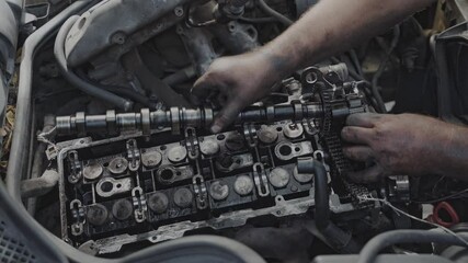A mechanic is repairing a car engine in a garage, demonstrating skills in vehicle maintenance and repair