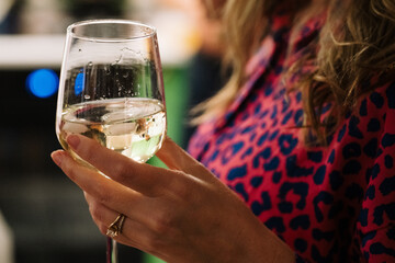 A woman is gracefully holding a glass of wine in her hand as she enjoys the moment. This gesture signifies relaxation and enjoyment