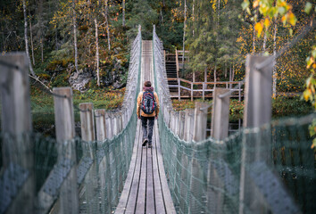 man in a yellow jacket crossing a suspension bridge in Finland