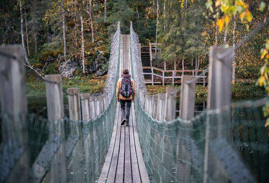 man in a yellow jacket crossing a suspension bridge in Finland