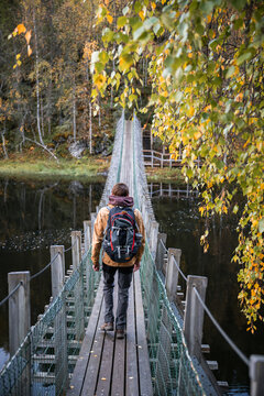 man in a yellow jacket crossing a suspension bridge in Finland