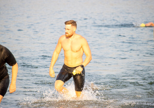 Triathlete exits water, completing the swim leg of the race