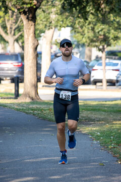 Male athlete running in a triathlon, wearing sunglasses and race gear