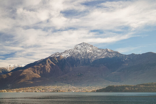 Snow caped mountain and a village against white cloud on a blue sky