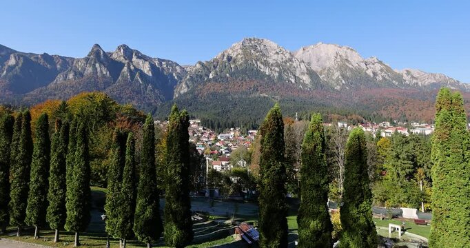 The Bucegi Mountains and Caraiman Peak in the background and Busteni city during a sunny autumn day.