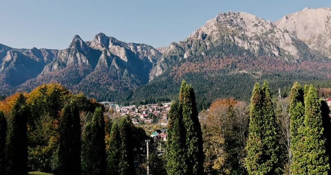 The Bucegi Mountains and Caraiman Peak in the background and Busteni city during a sunny autumn day.