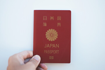 日本国のパスポートを持つ人の手元と白背景