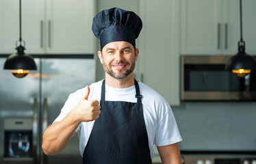 Happy chef cook with thumb up. Portrait of chef man in a chef cap in the kitchen. Man wearing apron and chefs uniform and chefs hat. Character kitchener, chef for advertising.
