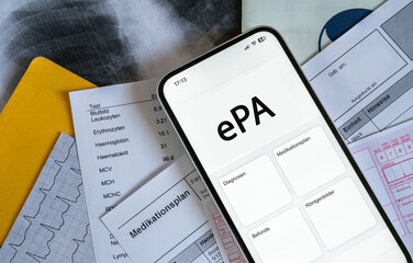 Ein Smartphone auf dem gerade eine elektronische Patientenakte angezeigt wird, liegt auf...