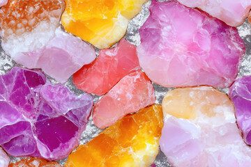 A seamless pattern featuring colorful gemstones in shades of pink, purple, orange, and yellow with a sparkling texture, ideal for decorative backgrounds and design elements.