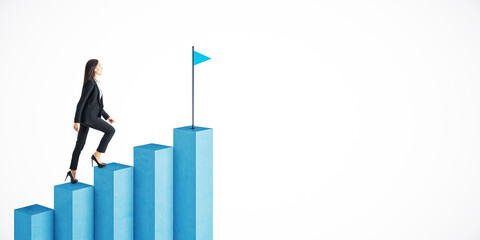Businesswoman climbing blue graph bars towards a flag symbolizing achievement on a white background.