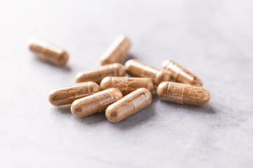 Ashwagandha (Withania somnifera) capsules. Concept for a healthy dietary supplementation. Bright stone background. Close up. Copy space.	