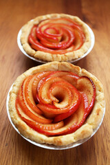 Pair of Freshly Baked Rose Shaped Apple Tartlets on Wooden Breadboard