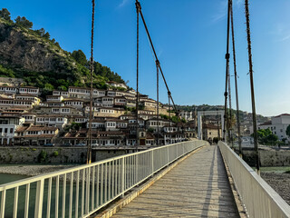 Gorica Bridge in tourist town of Berat nestled in valley between mountains in Albania, Europe. Footbridge crosses river Osum. UNESCO World Heritage Site with Ottoman architecture. City of windows