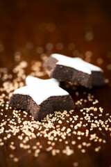 Christmas cookies (cinnamon stars) and brown sugar on dark background. Close up.	
