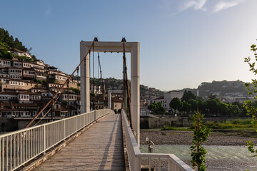 Fototapeta premium Gorica Bridge in tourist town of Berat nestled in valley between mountains in Albania, Europe. Footbridge crosses river Osum. UNESCO World Heritage Site with Ottoman architecture. City of windows