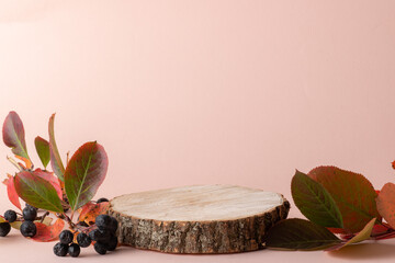 Wooden podium with autumn mountain ash leaves on a beige background.