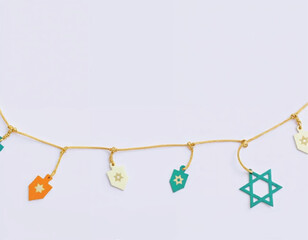 a Hanukkah garland with star of David icons on dreidels hanging from the string on lilac background