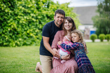 Fototapeta premium Family portrait, young couple and children posing in the backyard on the grass