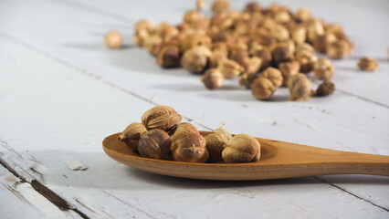Close-up of dried cardamom pods, amomum kravanh, scattered on a white wooden surface, ideal for illustrating spice-related content, natural products, or culinary themes