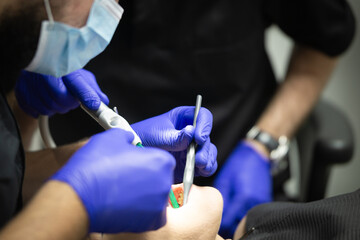 A doctor holds a dental instrument and treats a patient's teeth.