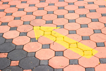Yellow arrow on orange and black brick block floor