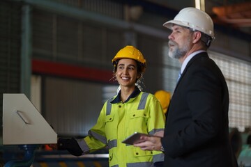 A woman worker in a yellow safety vest is talking to a foreman in a suit