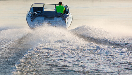 A man in a green shirt is riding a boat on a lake