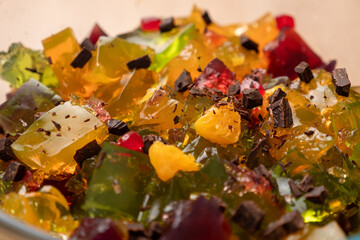 Multicolored crushed gelatin cubes are poured into a bowl. Preparation of gelatin desserts.
