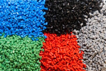 Pile of Plastic granules in the colors of blue, green, red and black and grey, colseup of polymer...