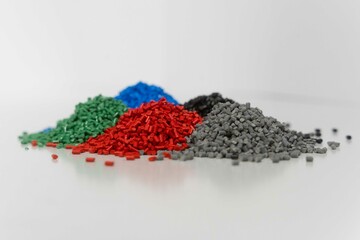 Pile of Plastic granules in the colors of blue, green, red and black and grey, colseup of polymer...