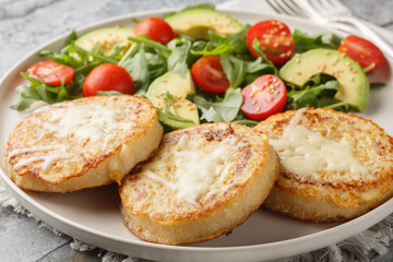 Cheesy Eggy Crumpets with salad made of avocado, tomato, arugula and spinach closeup on the plate on the table. Horizontal