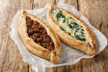 Turkish flat bread that comes stuffed with a variety of toppings, including cheese, spiced meat and spinach close-up on table. Horizontal