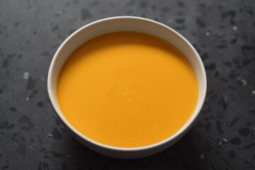 Pumpkin soup in white bowl on concrete background