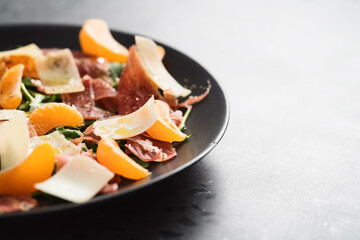 Salad with prosciutto, tangerines and vintage cheese with copy space