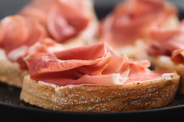 bruschetta with prosciutto and cream cheese on black plate closeup