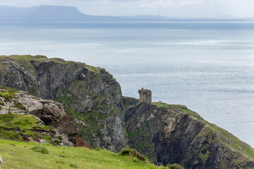 View of rugged cliffs meeting the ocean and sky near Slieve League, Ireland, with an old stone structure perched on the edge