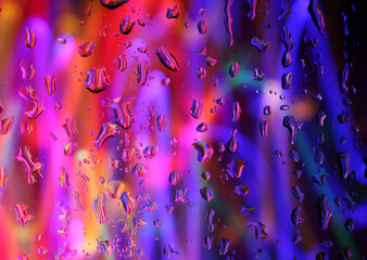 A long exposure photograph. Light painting photography - colourful fairy lights behind a wet pane of glass. Abstract background colour