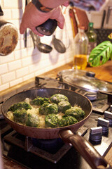 a man fries vegetables in a skillet on the stove