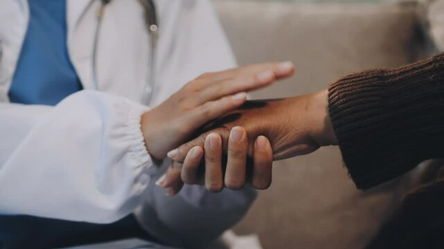 Doctor giving hope. Close up shot of young female physician leaning forward to smiling elderly lady patient holding her hand in palms. Woman caretaker in white coat supporting encouraging old person