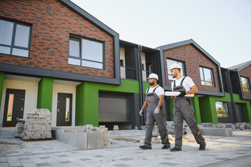 Two builders on the background of new cottages. The work is done
