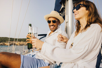 Happy couple celebrating on a yacht with champagne, enjoying a relaxing and luxurious day at sea under the sun.
