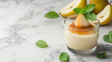 Pear and vanilla panna cotta, isolated on a marble background with caramelized pear slices and fresh mint leaves