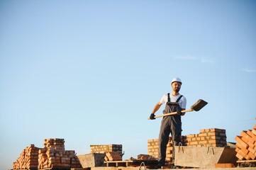construction mason worker bricklayer installing red brick with trowel putty knife outdoors