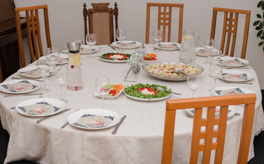 The round table is served with plates and accessories, some snacks and drinks are already assembled, chairs around the table.