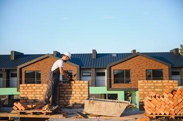 Installing brick wall. Construction worker in uniform and safety equipment have job on building