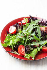 Salad with fresh tomatoes and arugula on a bright stone background. Close up. Copy space.	